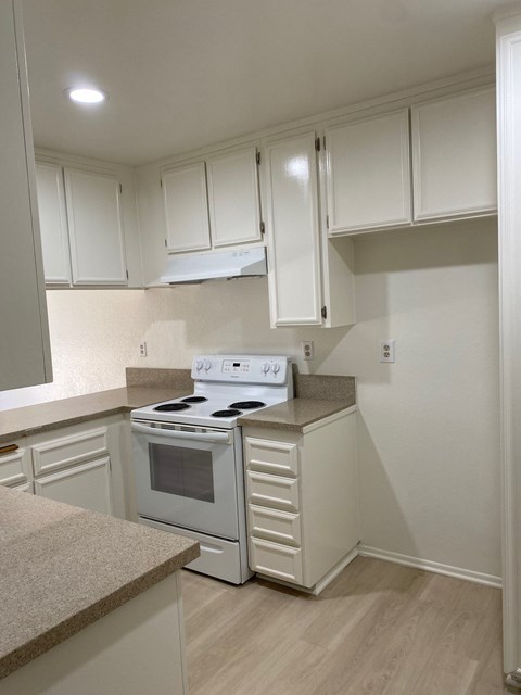 an empty kitchen with white cabinets and a white stove